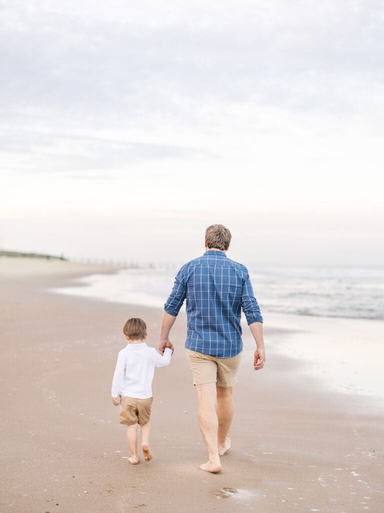 Dad and son walking and holding hands at the beach 