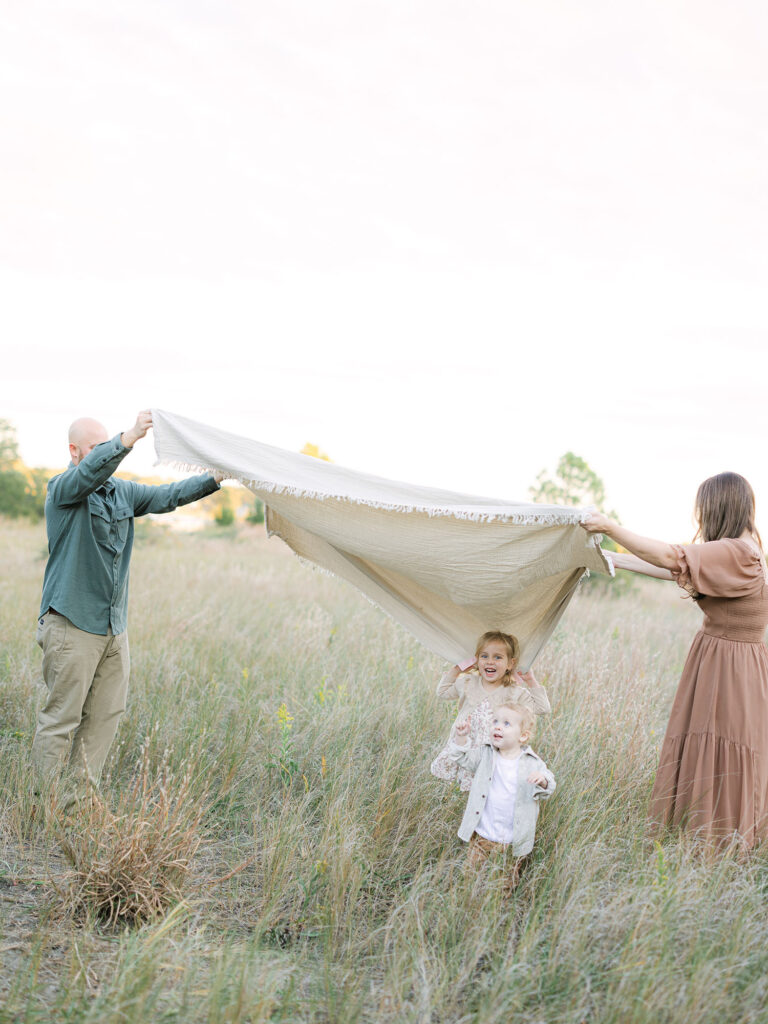 Mom and dad holding blanket for kids at Pleasure House point field 