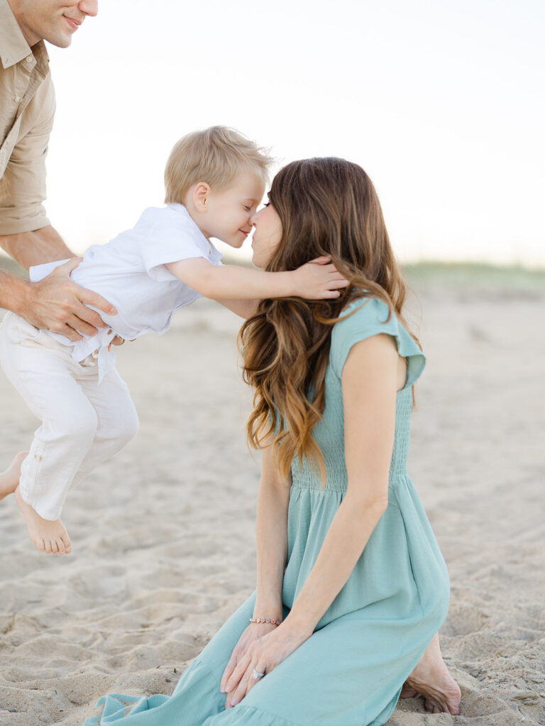 Mom dressed in teal kissing son on north end beach 