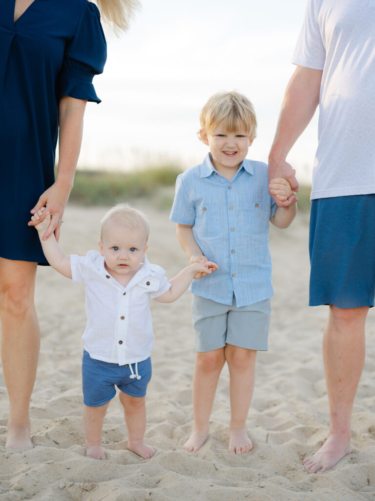 Two toddler boys dressed in blue holding mom and dads hands by Norfolk family photographer Ashley Brickner 