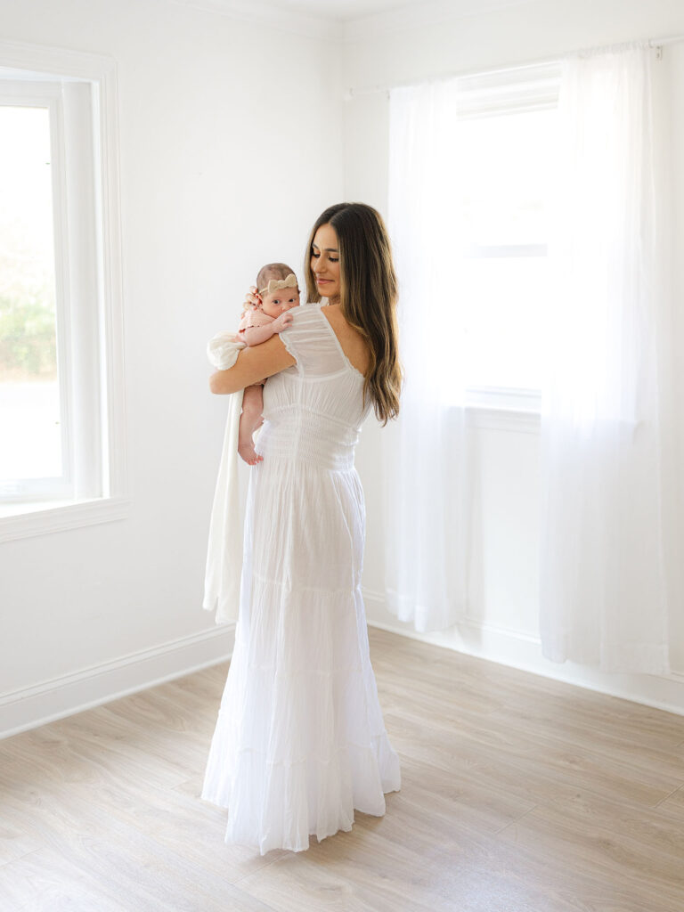 Mother in white maxi dress holding newborn baby girl for a Hampton Roads Newborn Photography session by Ashley Brickner 