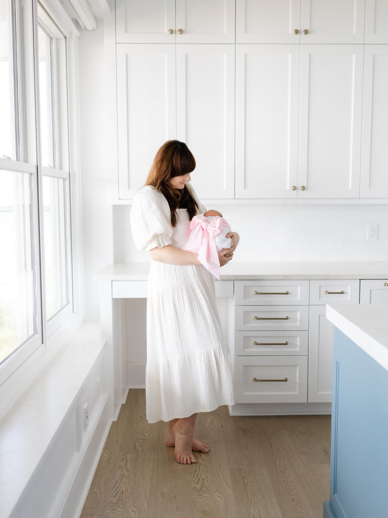 New mom dressed in white maxi dress holding newborn baby girl for Hampton Roads newborn photography session by Ashley Brickner 