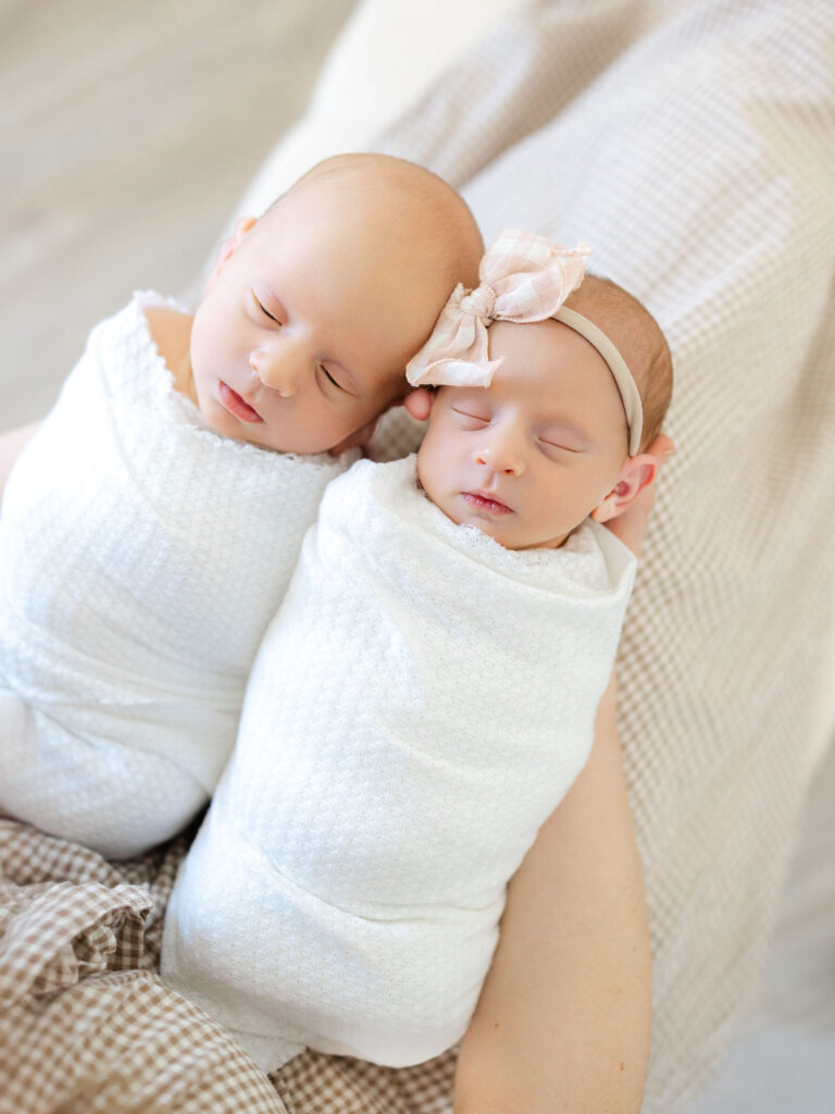 Swaddled twin babies in moms arms in studio in Hampton Roads 