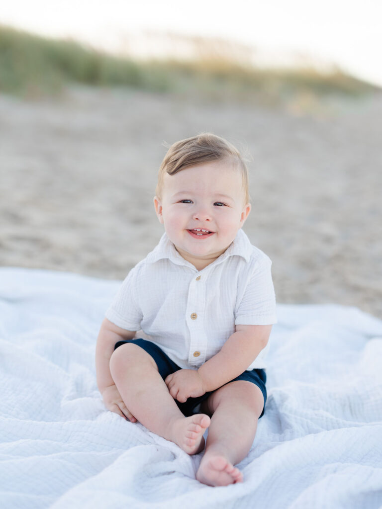 Boy in white and blue sitting on white blanket on Sandbridge beach