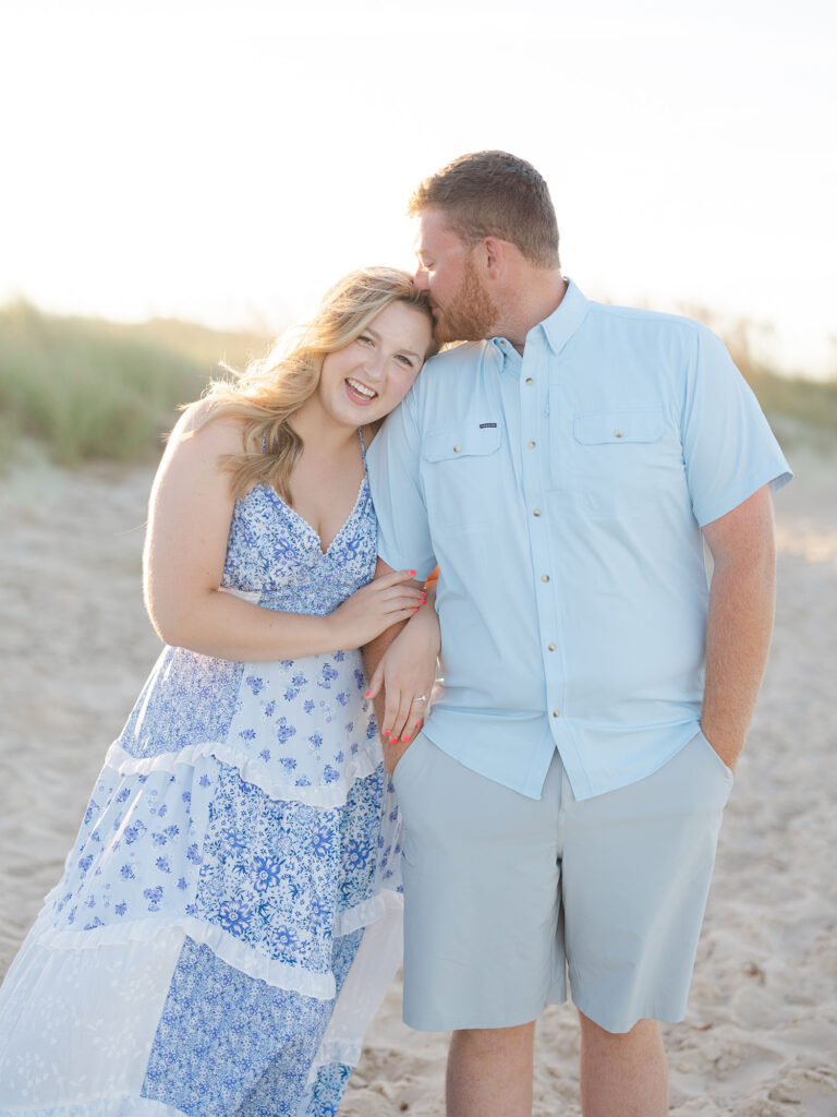 Man kissing woman on Sandbridge beach for photos