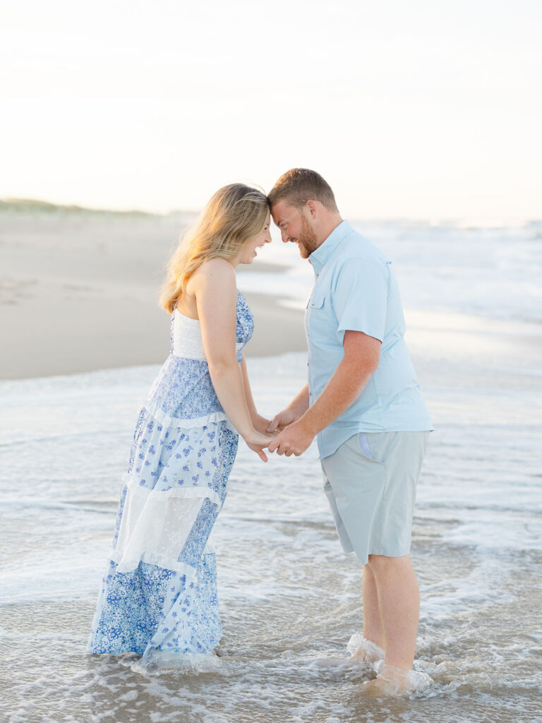 Couple dressed in blue and white touching foreheads on Sandbridge beach 