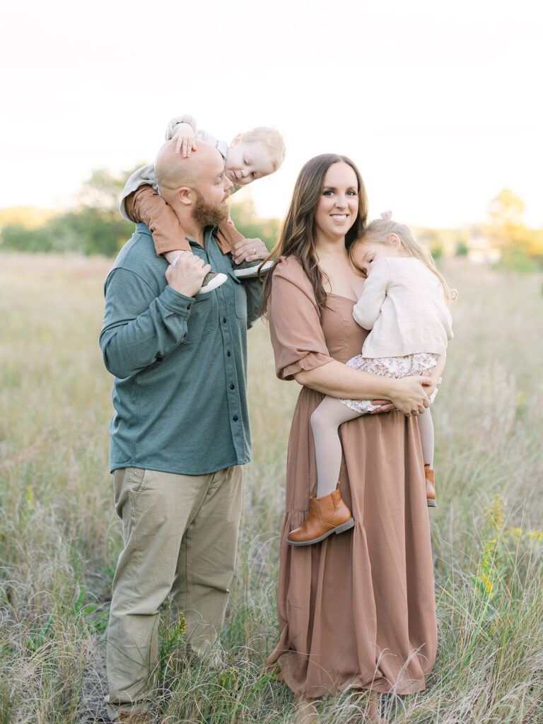 Family of four cuddling in a field by Hampton Roads Family Photographer Ashley Brickner 