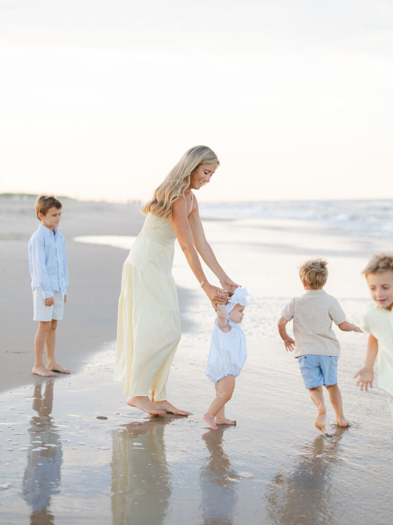 Mom and four kids dressed in blue and yellow playing at the water at the north end beach