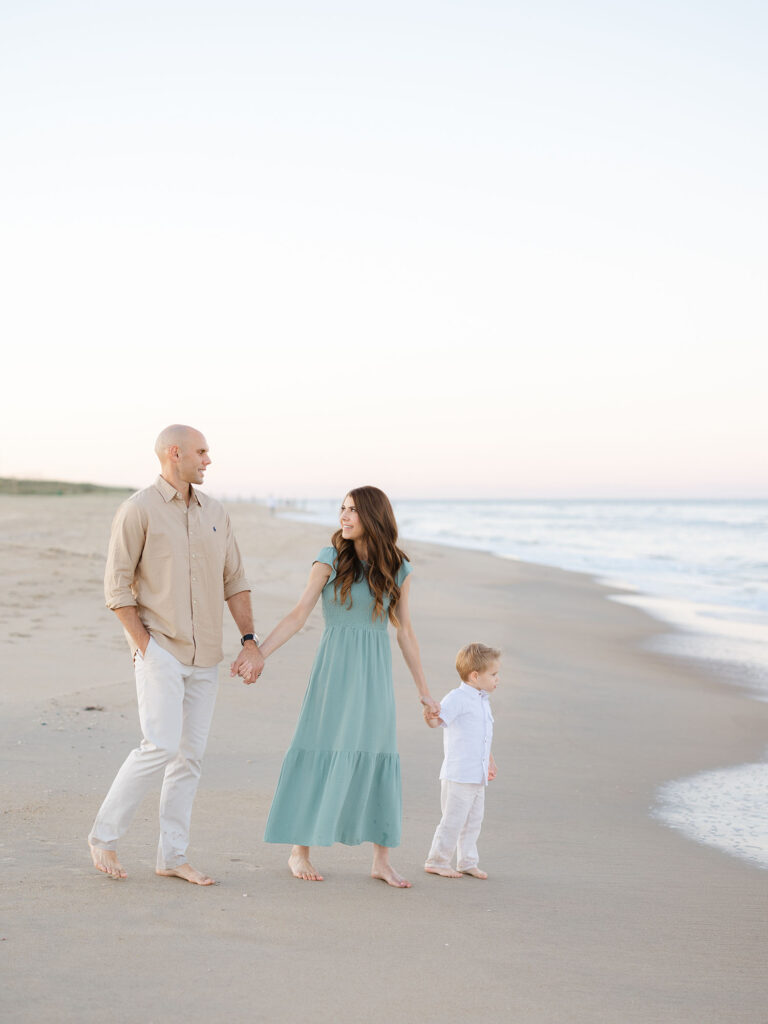 Family of three holding hands and walking on the beach by Virginia Beach family portraits photographer Ashley Brickner