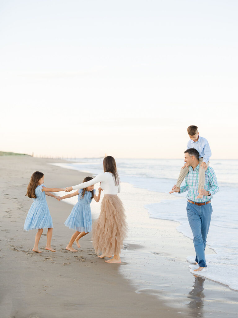 Family of five dressed in blue and tan playing at the water at the north end beach
