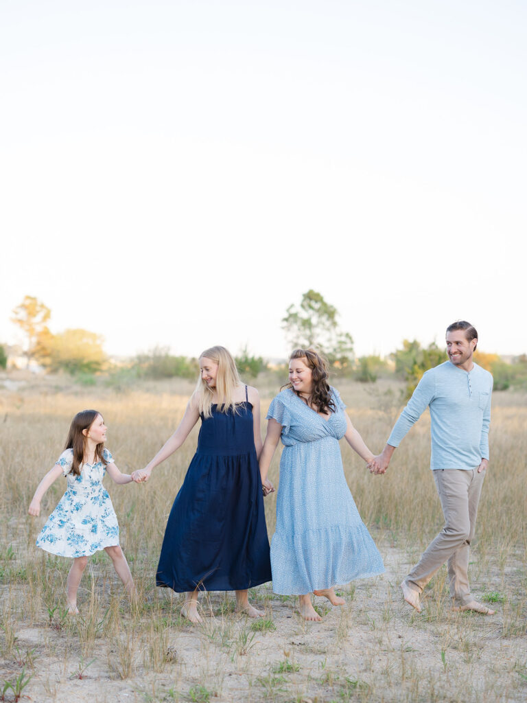 Family of four walking in field in blue during a Virginia Beach Mini Session by Ashley Brickner 
