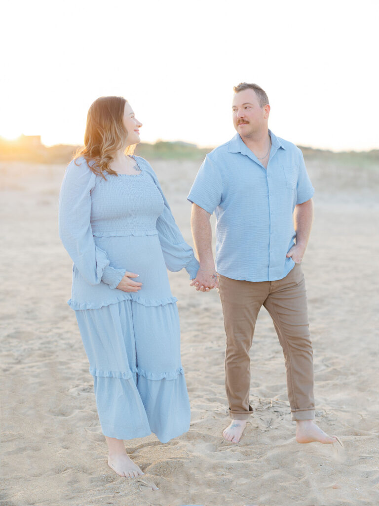 Pregnant women and man walking hand in hand on beach during Virginia Beach Mini Session 