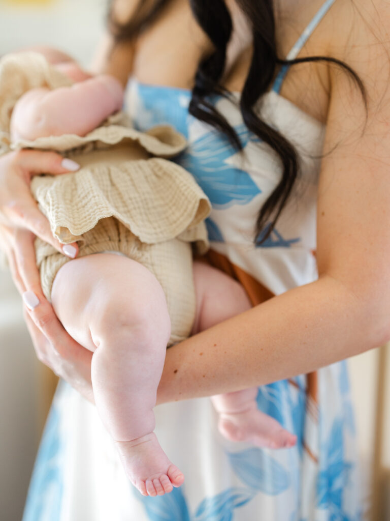 Mom holding newborn girl in nursery by Virginia newborn photographer Ashley Brickner 