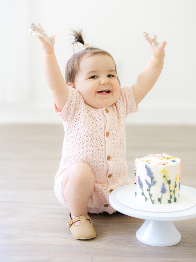 Toddler girl in front of floral cake in Hampton Roads studio