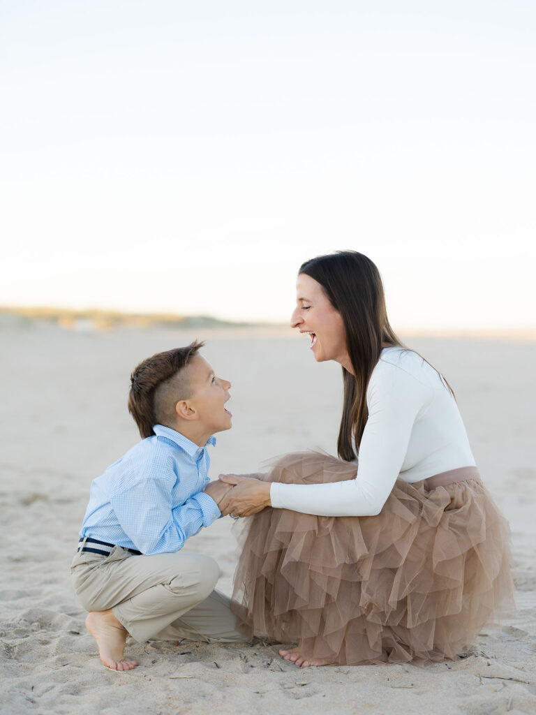 Mom and son holding hands and laughing on beach by Virginia Beach mom and family photographer Ashley Brickner 