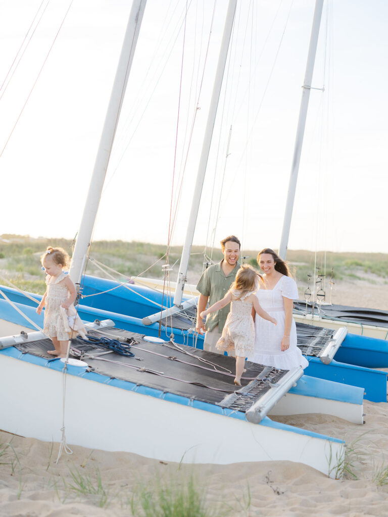 Family of four playing on boat on the beach for Virginia Beach summer photos by Ashley Brickner 