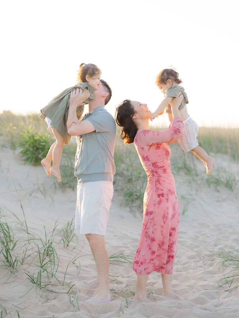 Family of four in pink and green standing on beach for Virginia Beach summer photos by Ashley Brickner 