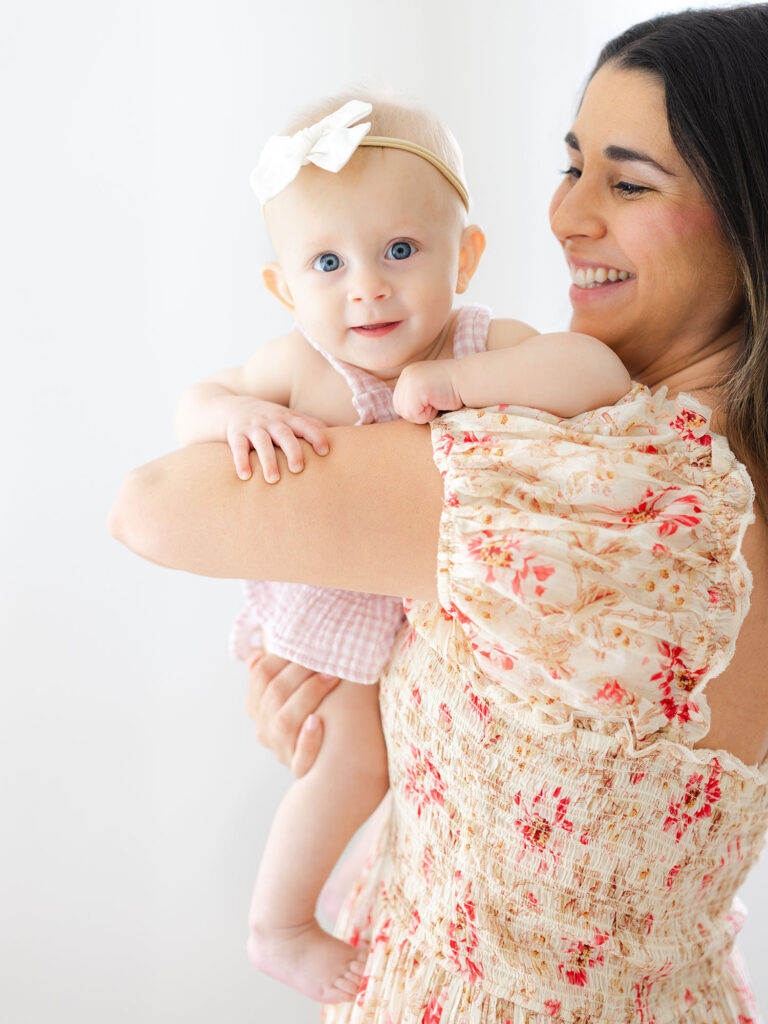 Mom in floral dress holding baby girl during a milestone session photography by Virginia Beach photographer Ashley Brickner 
