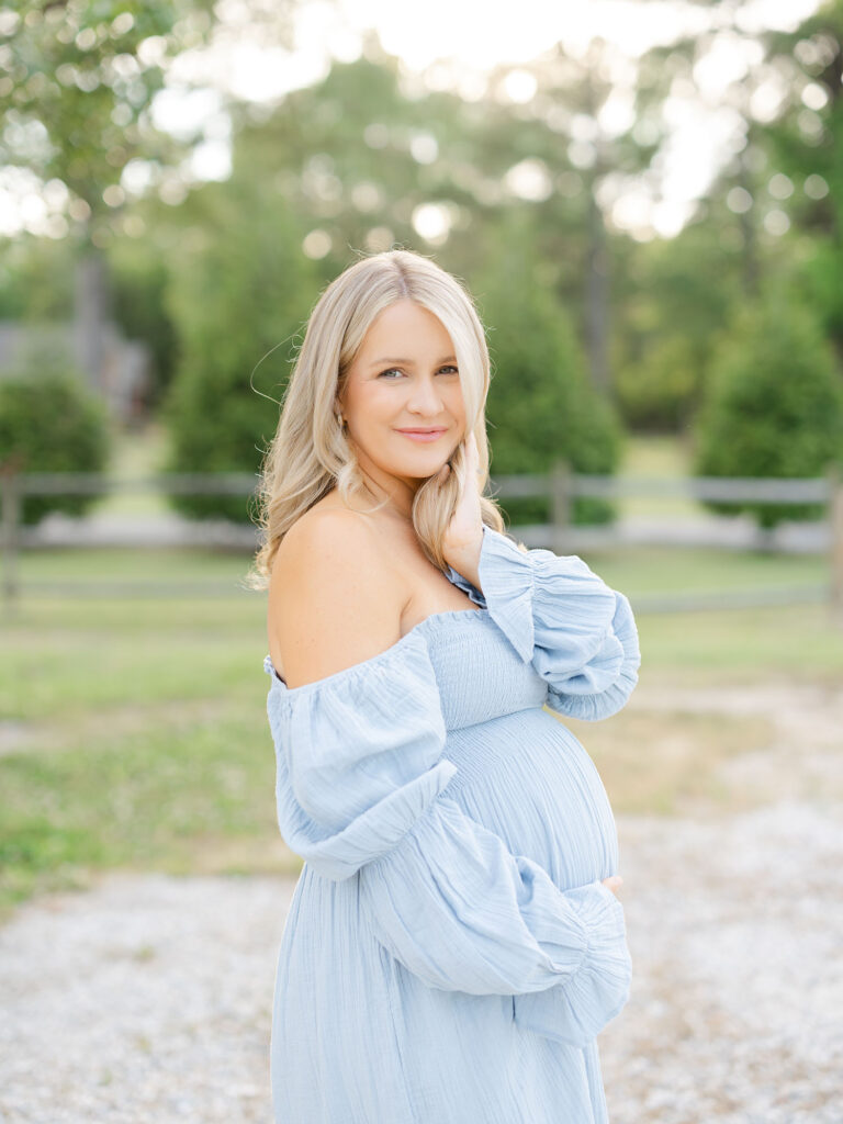 Pregnant mom in blue dress in field posing for her summer maternity photos by Ashley Brickner 
