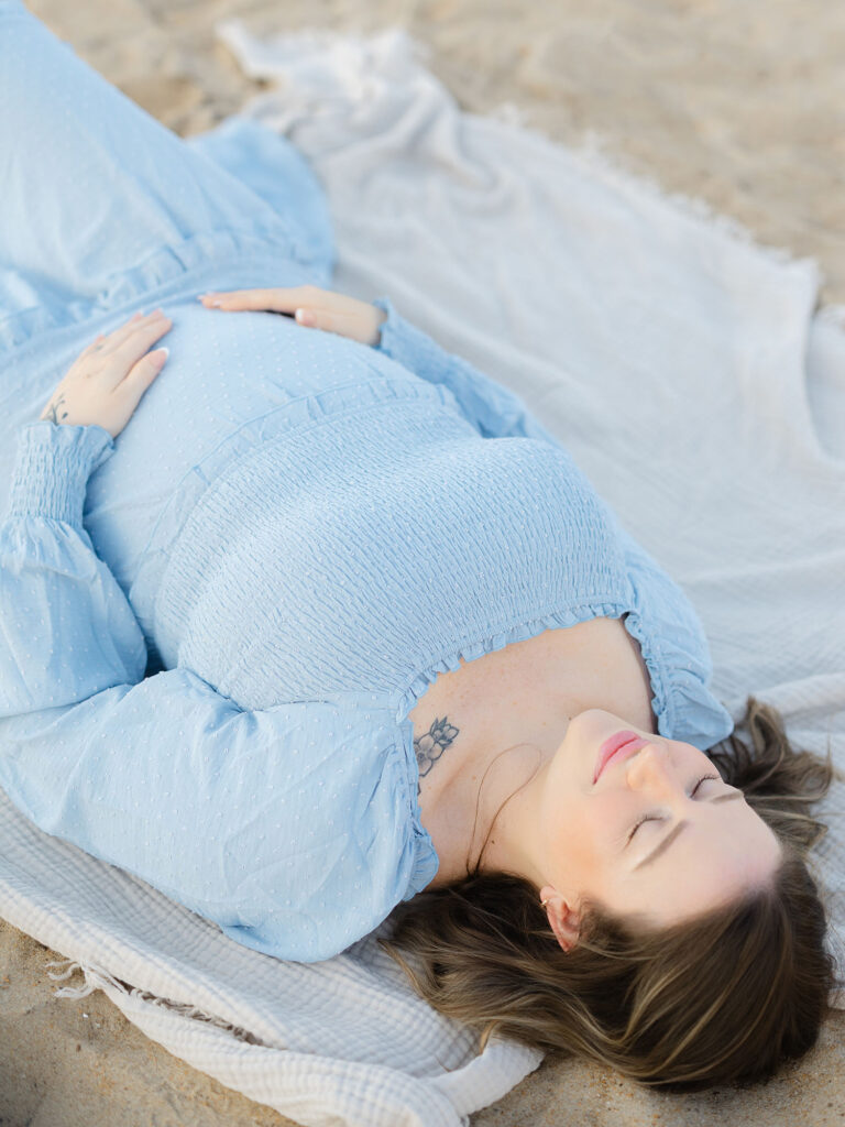 Pregnant mom in blue holding her belly for her summer maternity photos in Virginia Beach by Ashley Brickner 
