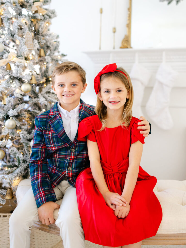 Brother and sister in Christmas colors in front of tree photographed for Santa mini session by Virginia Beach family photographer Ashley Brickner 