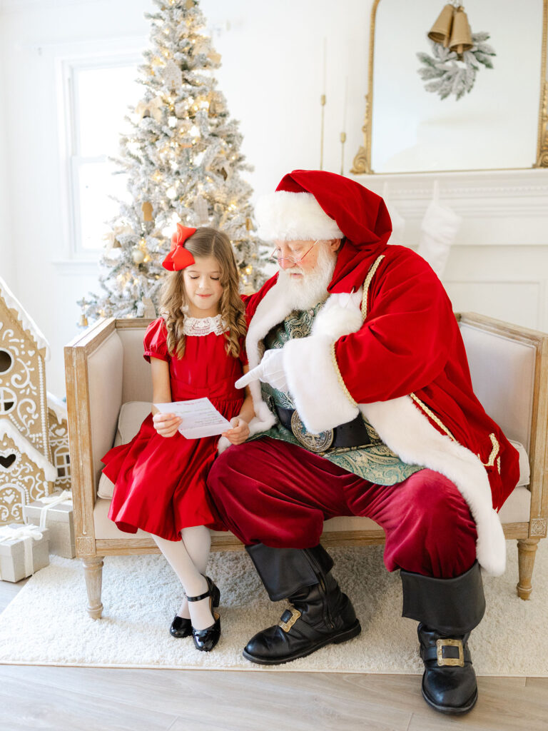 Santa and little girl looking at wish list photographed for santa mini session by Virginia Beach family photographer Ashley Brickner 